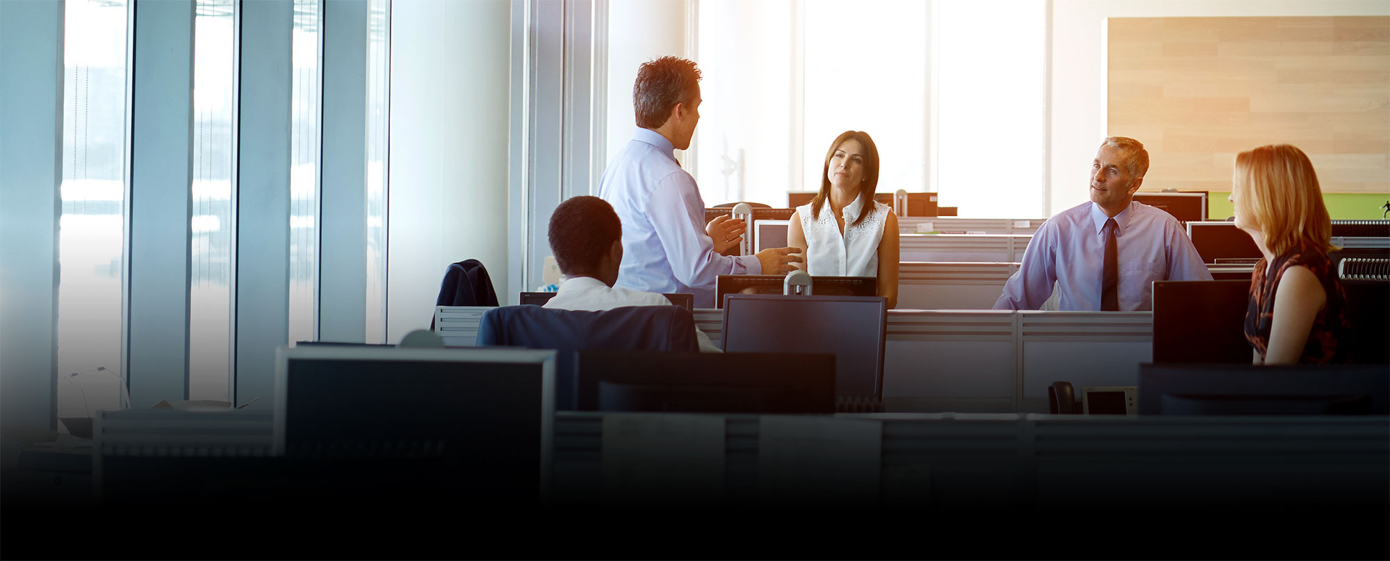 Office workers talking to each other next to computers