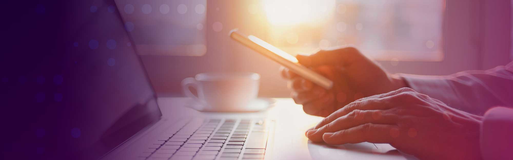 Close-up of hands on a laptop and holding a mobile phone